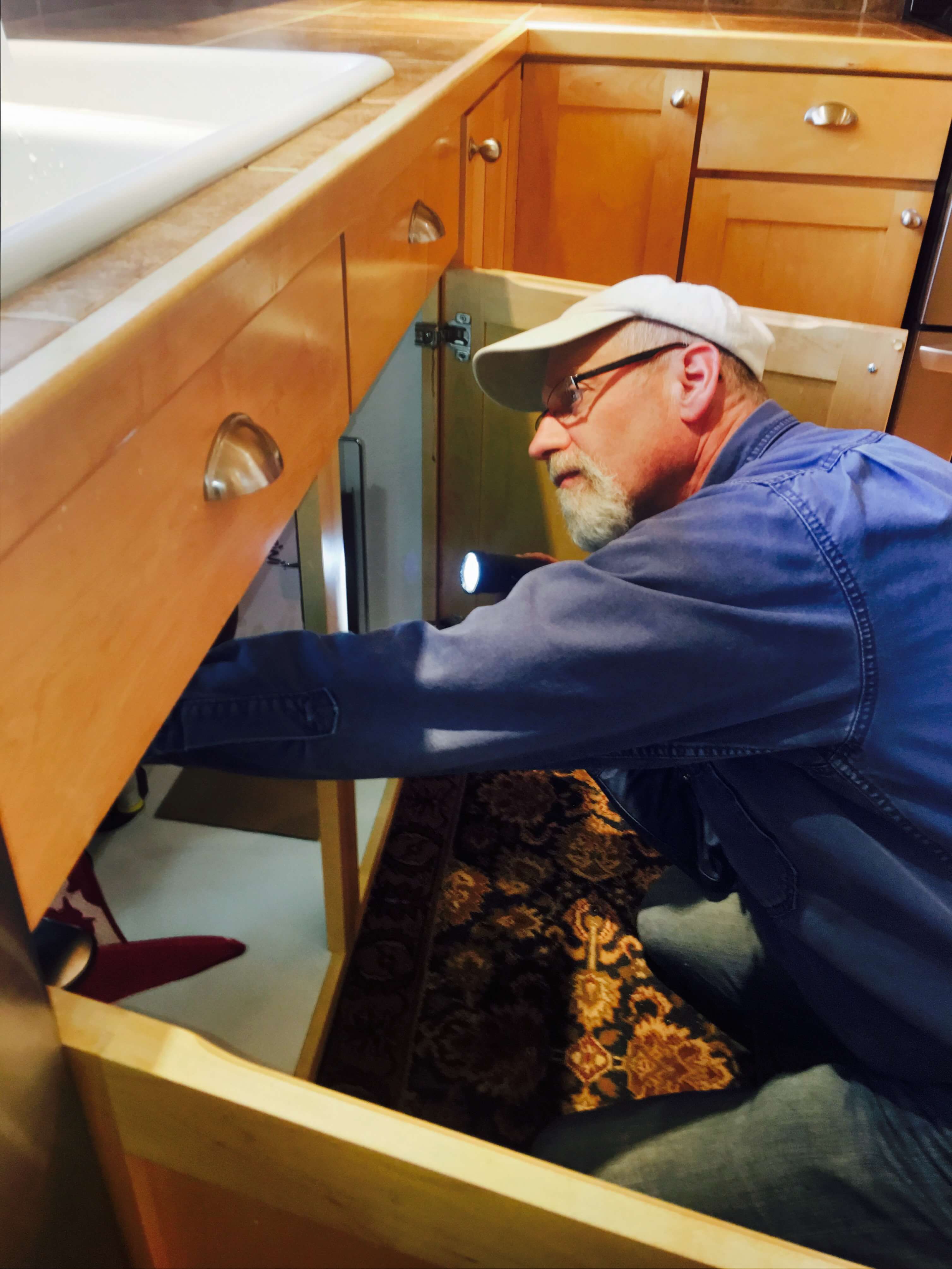 inspecting plumbing in kitchen